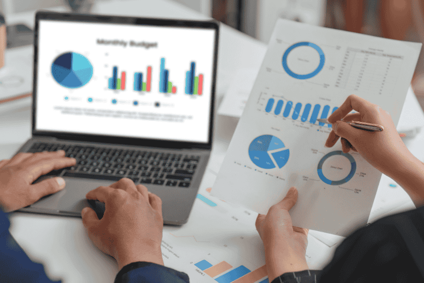 Coppia che analizza grafici di budget mensile al computer per valutare l’impatto del Buy Now Pay Later sul bilancio familiare.