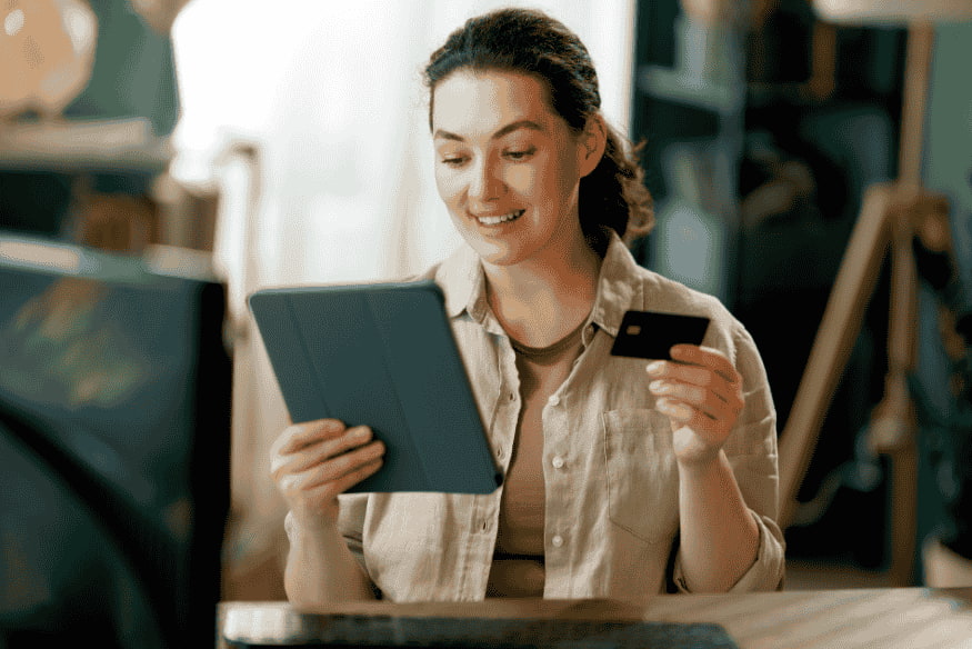 Donna che fa shopping online con carta di pagamento e tablet utilizzando il servizio Buy Now Pay Later per rateizzare gli acquisti.