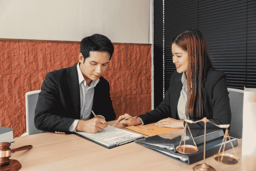 Due professionisti in ufficio discutono e firmano documenti relativi a una prestazione occasionale o ritenuta d’acconto.