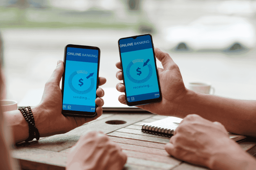 Bonifico tra smartphone con app di online banking per separare entrate, spese fisse e spese quotidiane