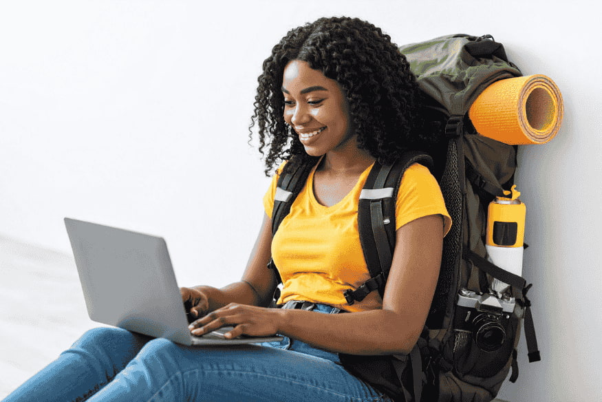 Viaggiatrice con zaino da backpacker che controlla online le proprie finanze durante un soggiorno all’estero